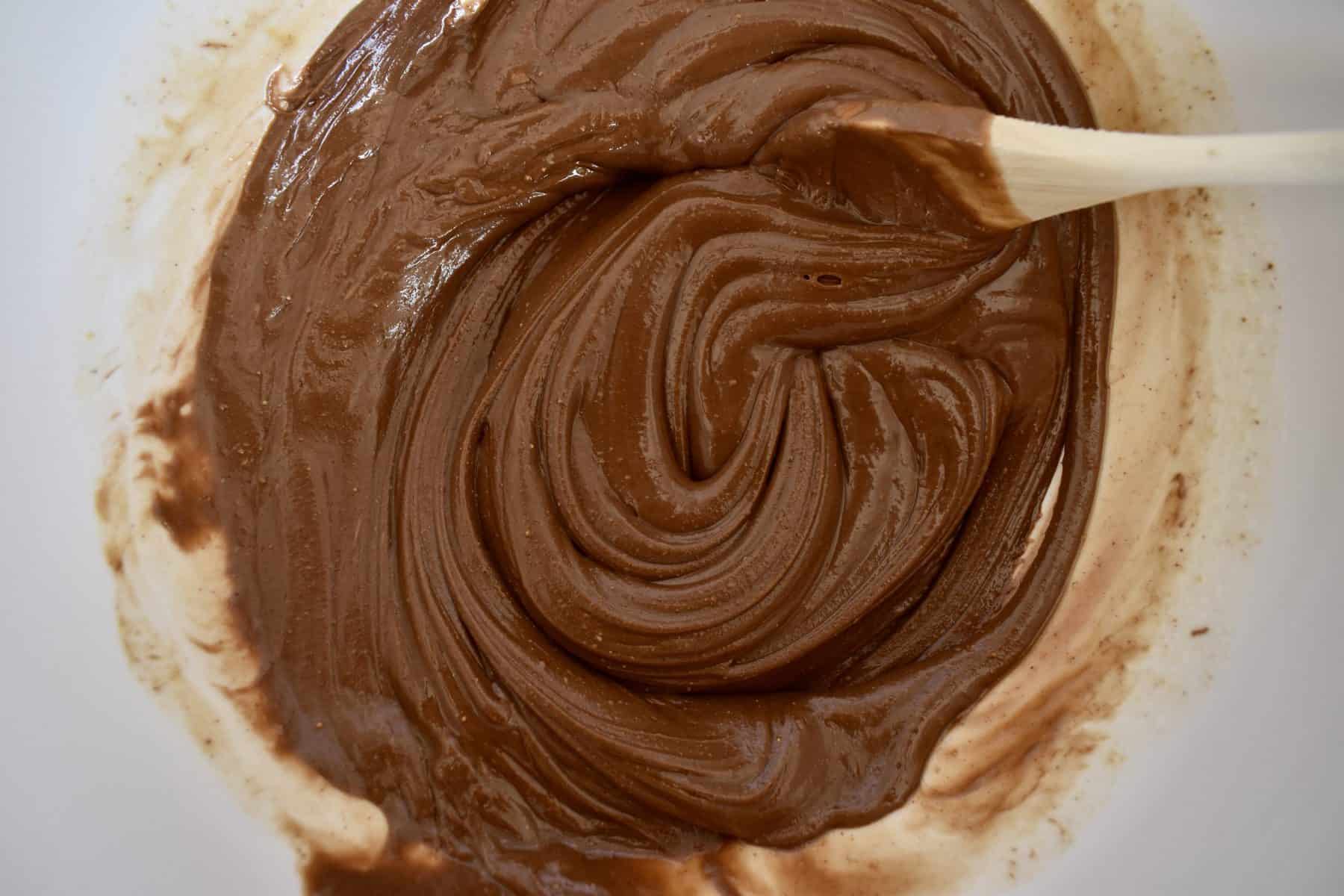 Nutella, peanut butter, and melted butter stirred together in a large white bowl. 