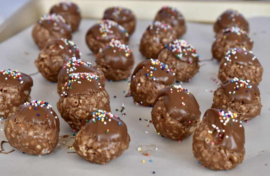 Chocolate topped Nutella balls with sprinkles on top on a cookie sheet.