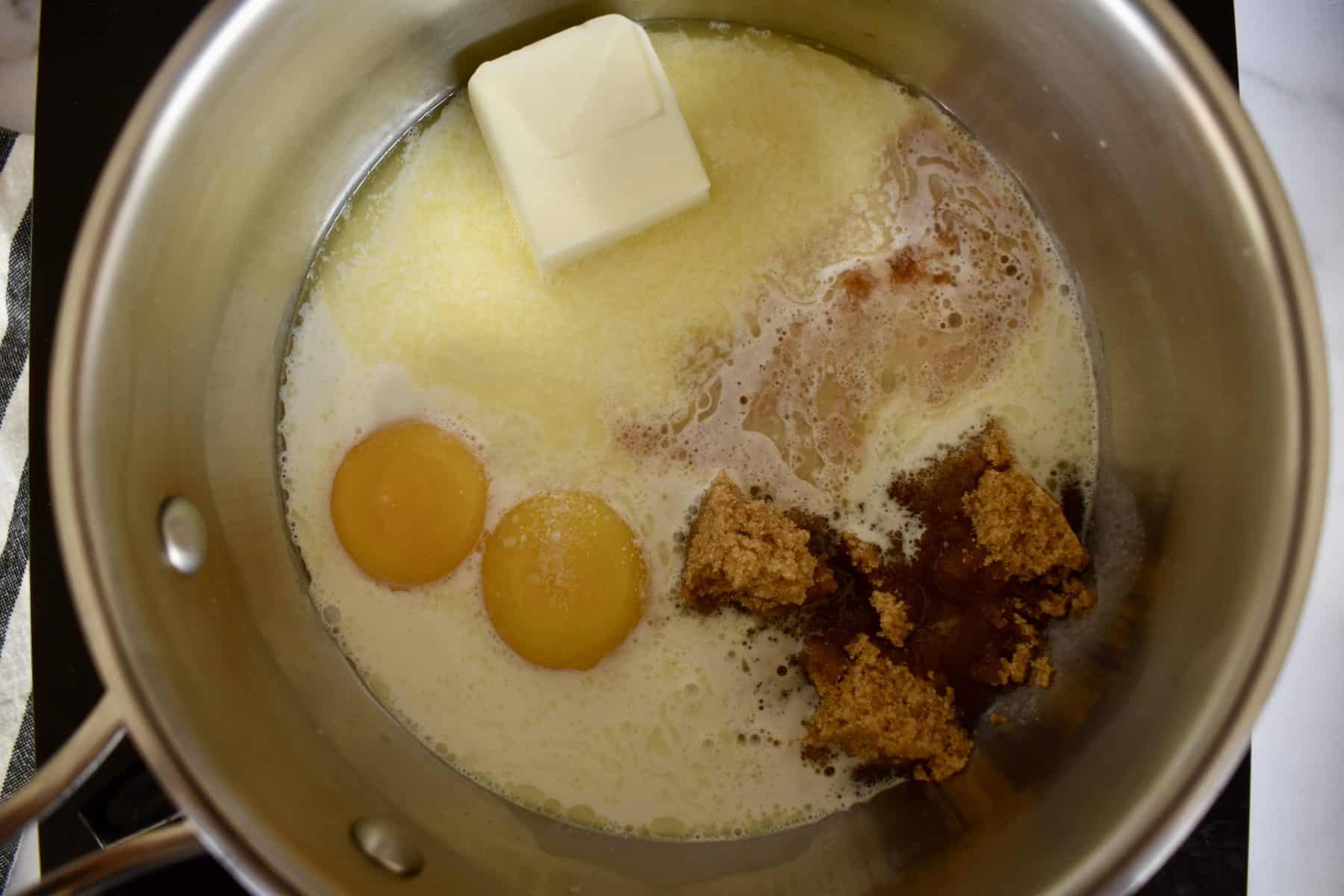 overhead photo of eggs, milk, brown sugar and vanilla in a saucepan. 