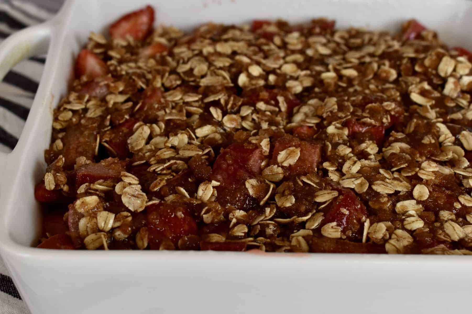 strawberry rhubarb crisp in a white baking dish ready to be baked. 