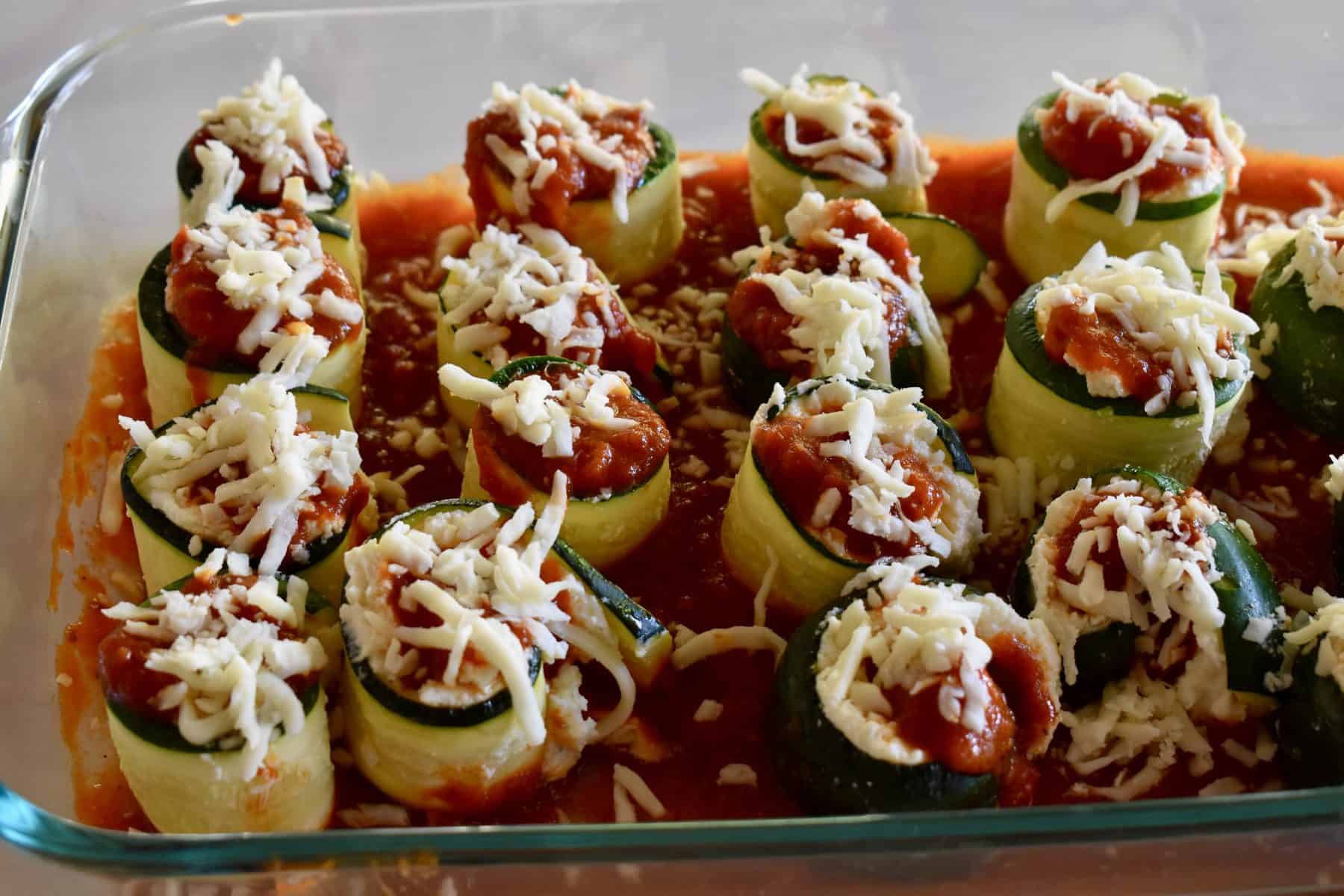 Zucchini rolls ups in a pan of marinara sauce.