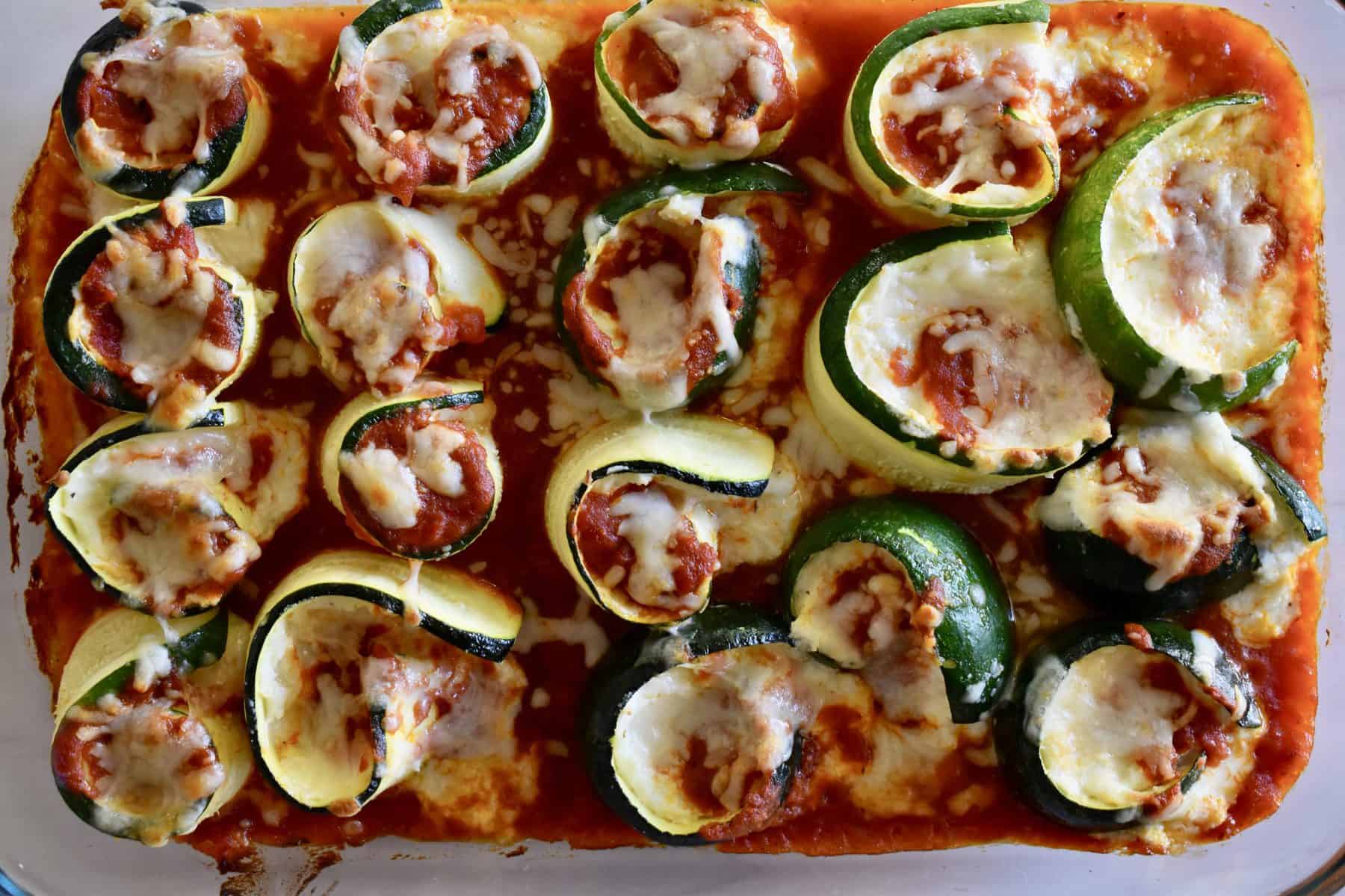 Overhead photo of zucchini ricotta rolls ups in a glass pan. 