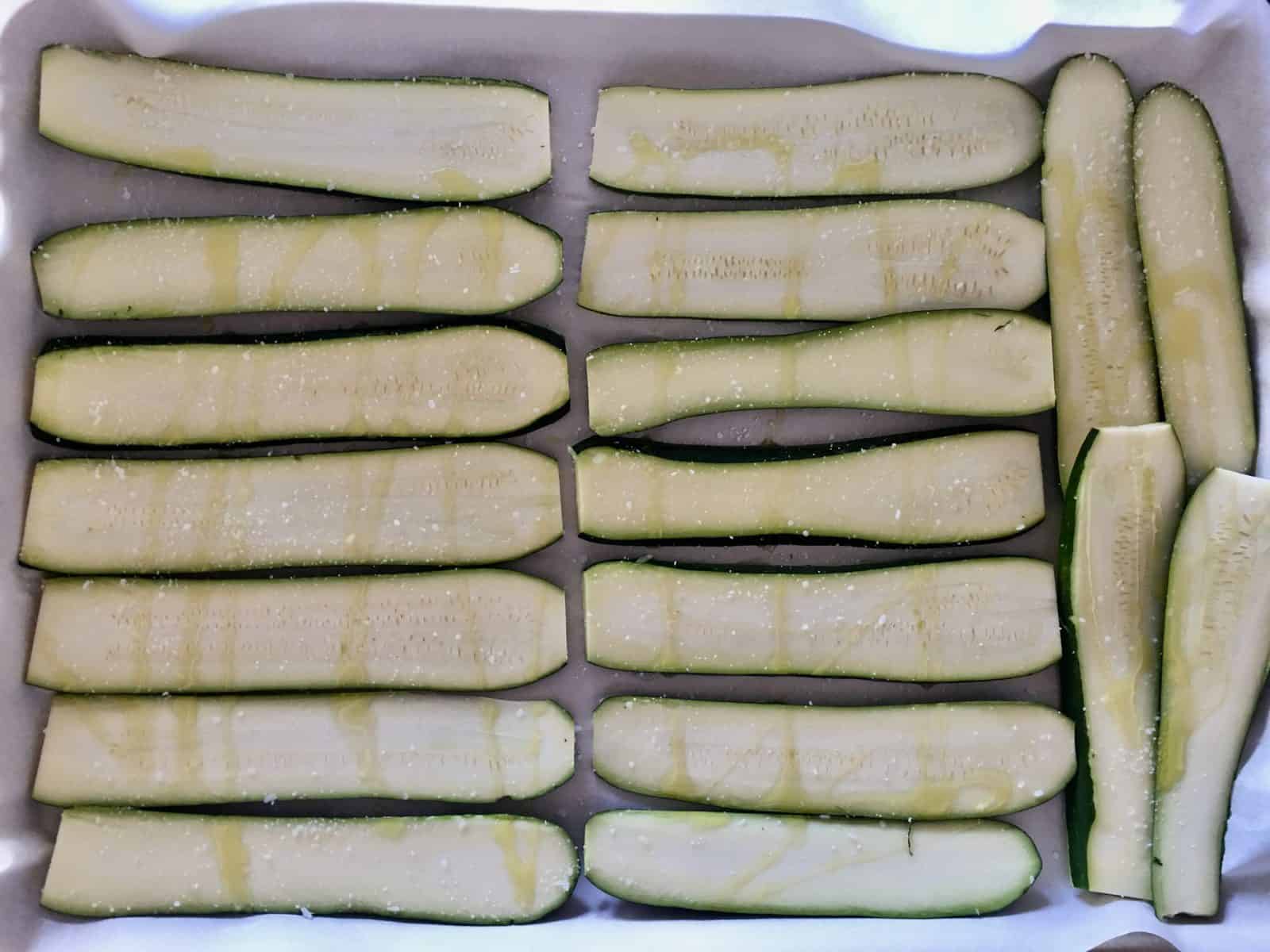 Sliced Zucchini on parchment paper on a baking sheet.