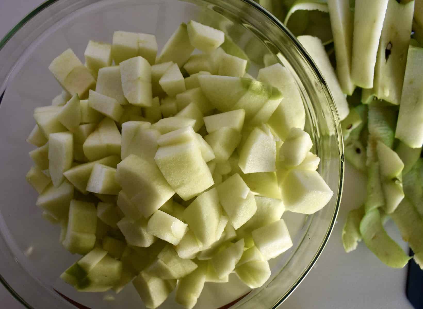 overhead photo of diced apples in a bowl with peels next to it. 
