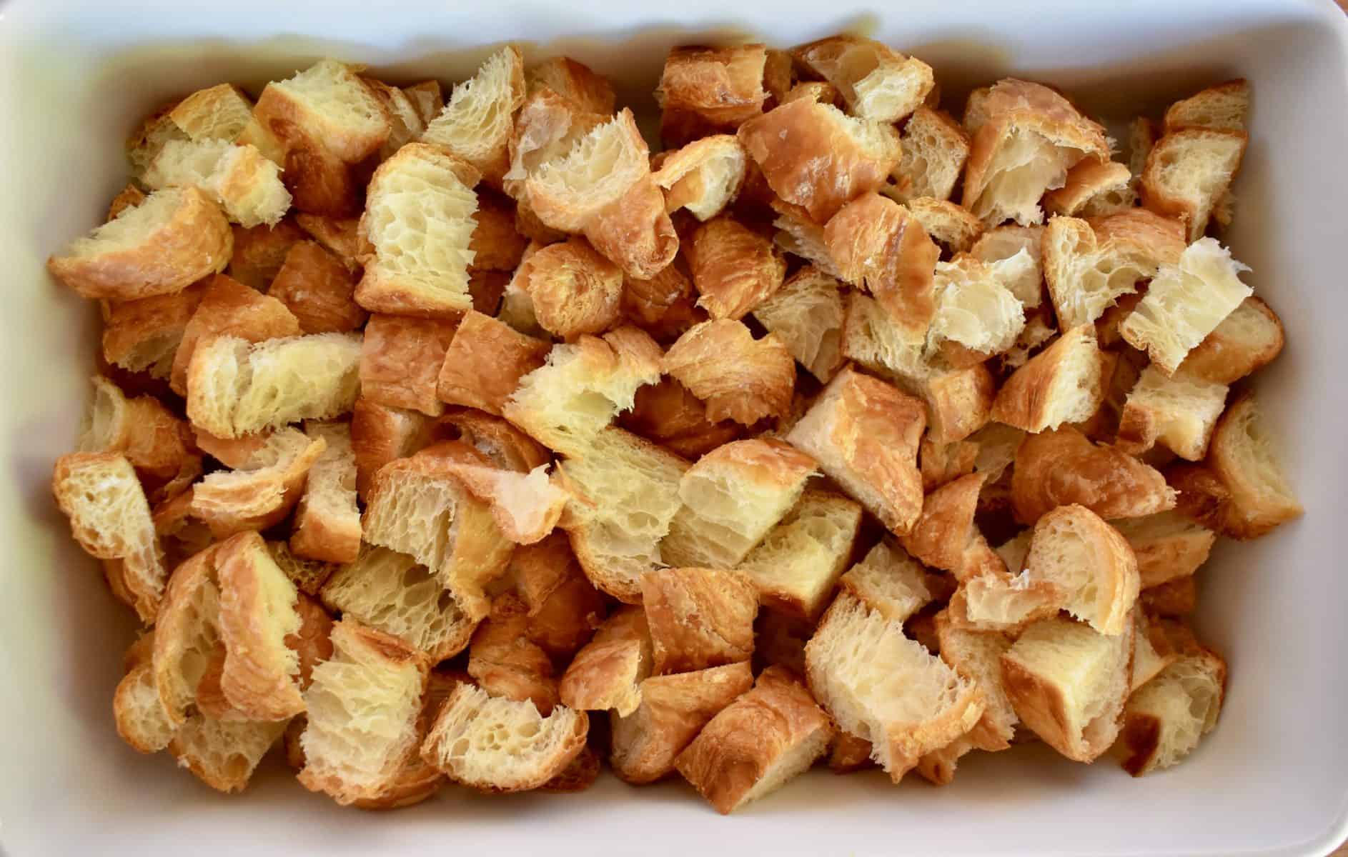 large chunks of croissant in a white baking dish. 