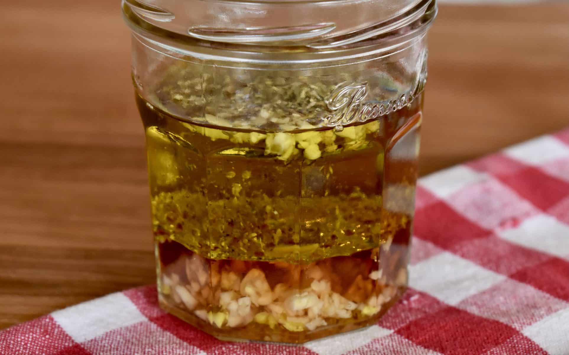 Italian dressing mixture in a glass jar on a wooden cutting board. 