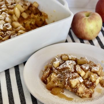 Croissant Baked French Toast in a dish with apples behind it.