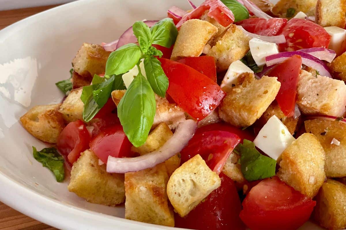 Bruschetta salad in a large white platter with a basil leave on top. 