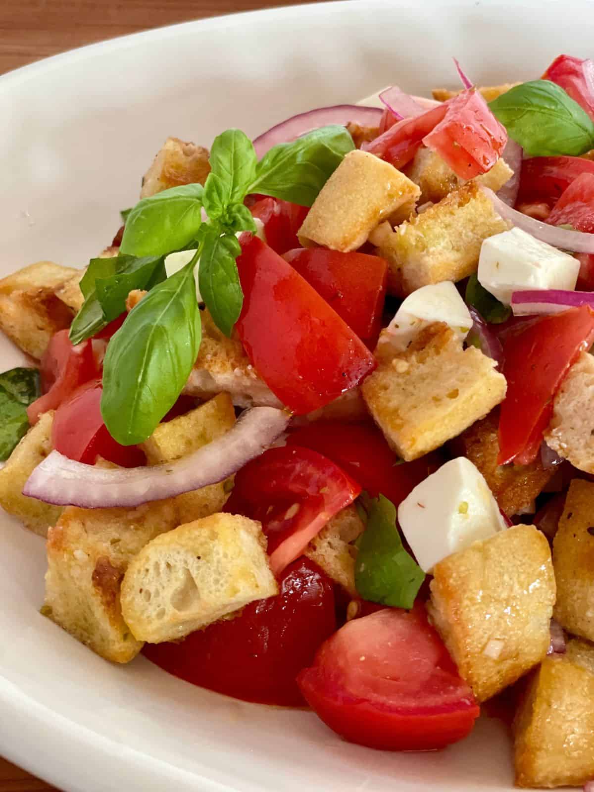 Bruschetta Salad with tomatoes, mozzarella, and bread in a white serving plate. 