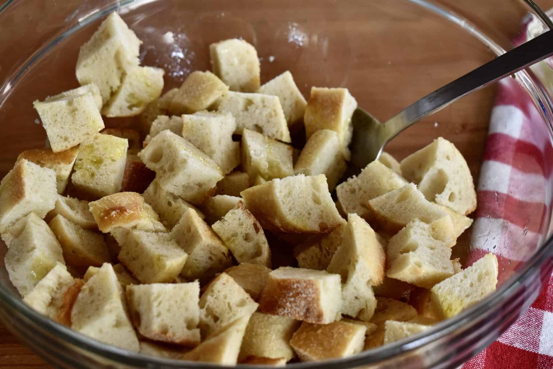 bread cubes in a glass bowl with a spoon in it. 