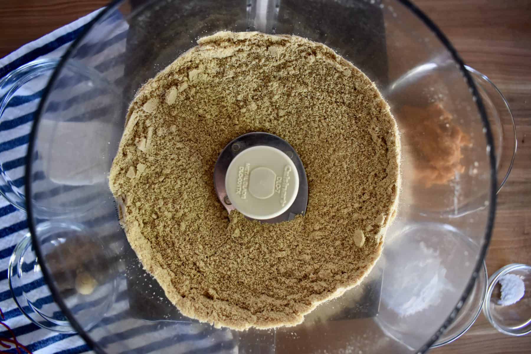 overhead photo of graham cracker crumbs in a food processor. 