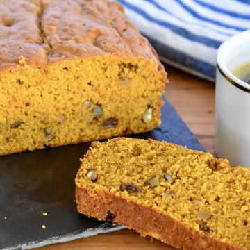 Pumpkin Walnut Raisin Bread on a cutting board with a cup of coffee.