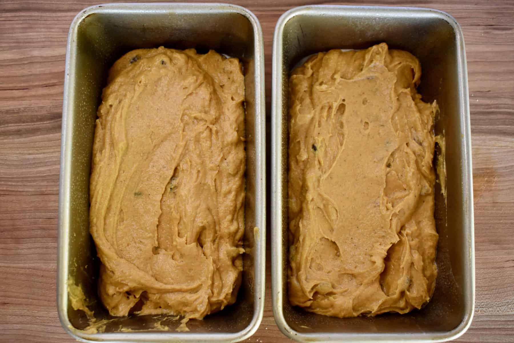 overhead photo of pumpkin walnut raisin bread batter in two loaves pans. 