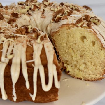 Pineapple Bundt Cake with no cake mix on a pedestal with cream cheese frosting.