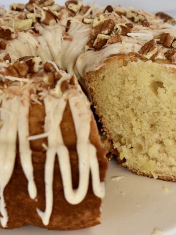 Pineapple Bundt Cake with no cake mix on a pedestal with cream cheese frosting.