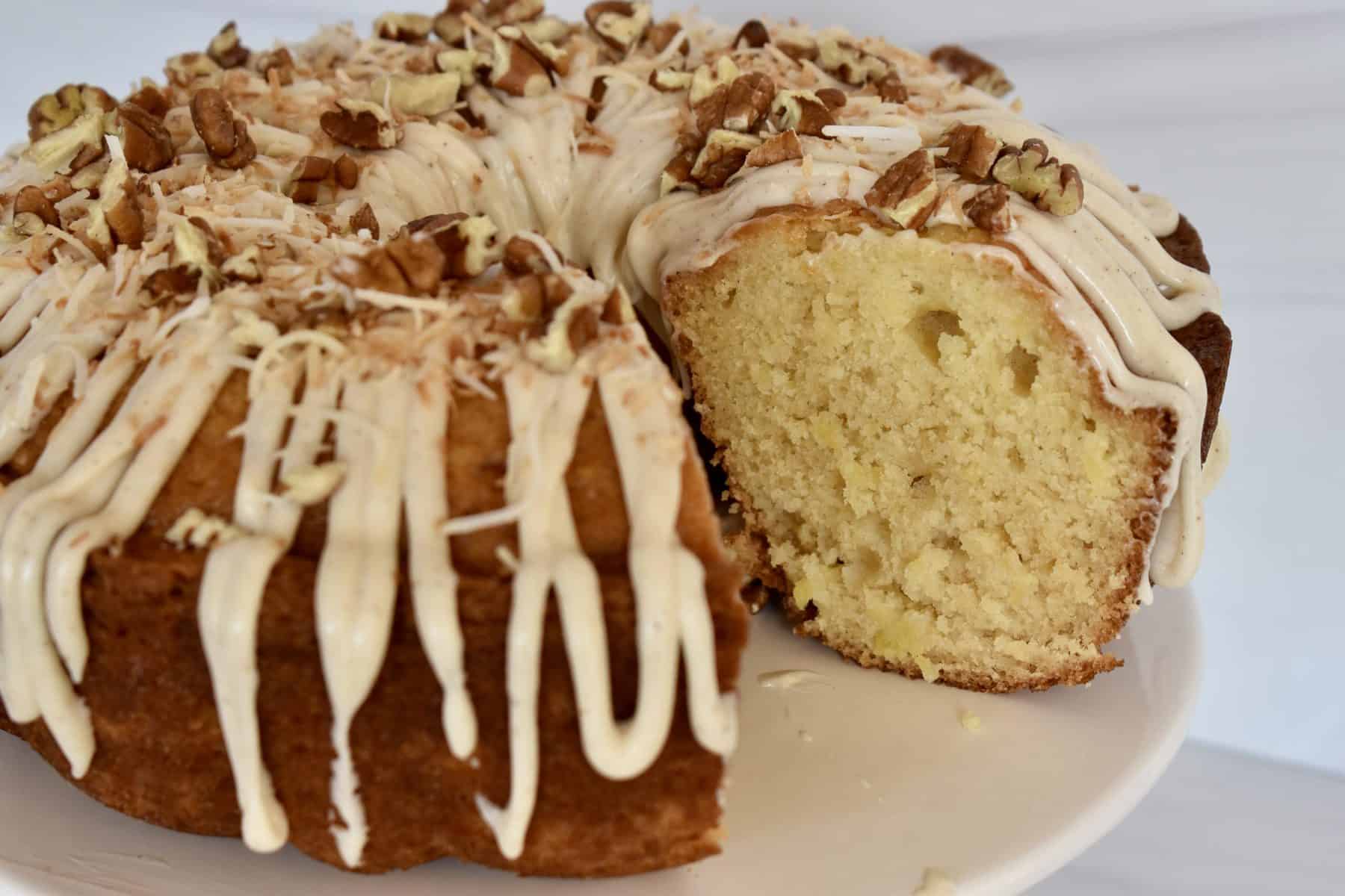Pineapple Bundt Cake with no cake mix on a pedestal with cream cheese frosting. 