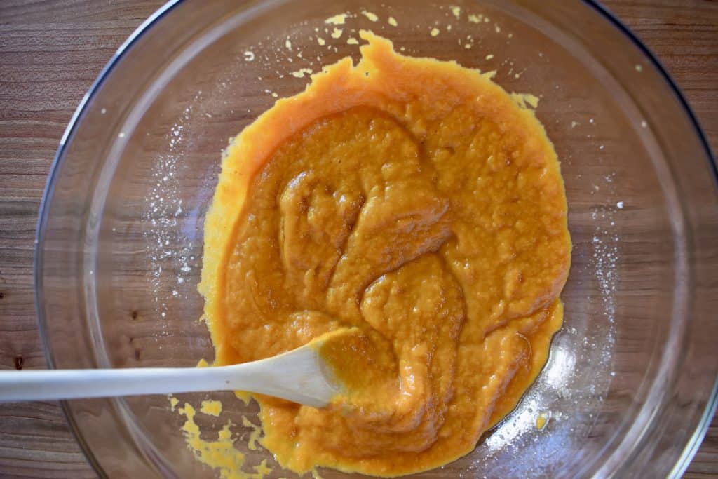 overhead photo of pumpkin puree, egg, butter, and vanilla mixed together in a glass bowl. 