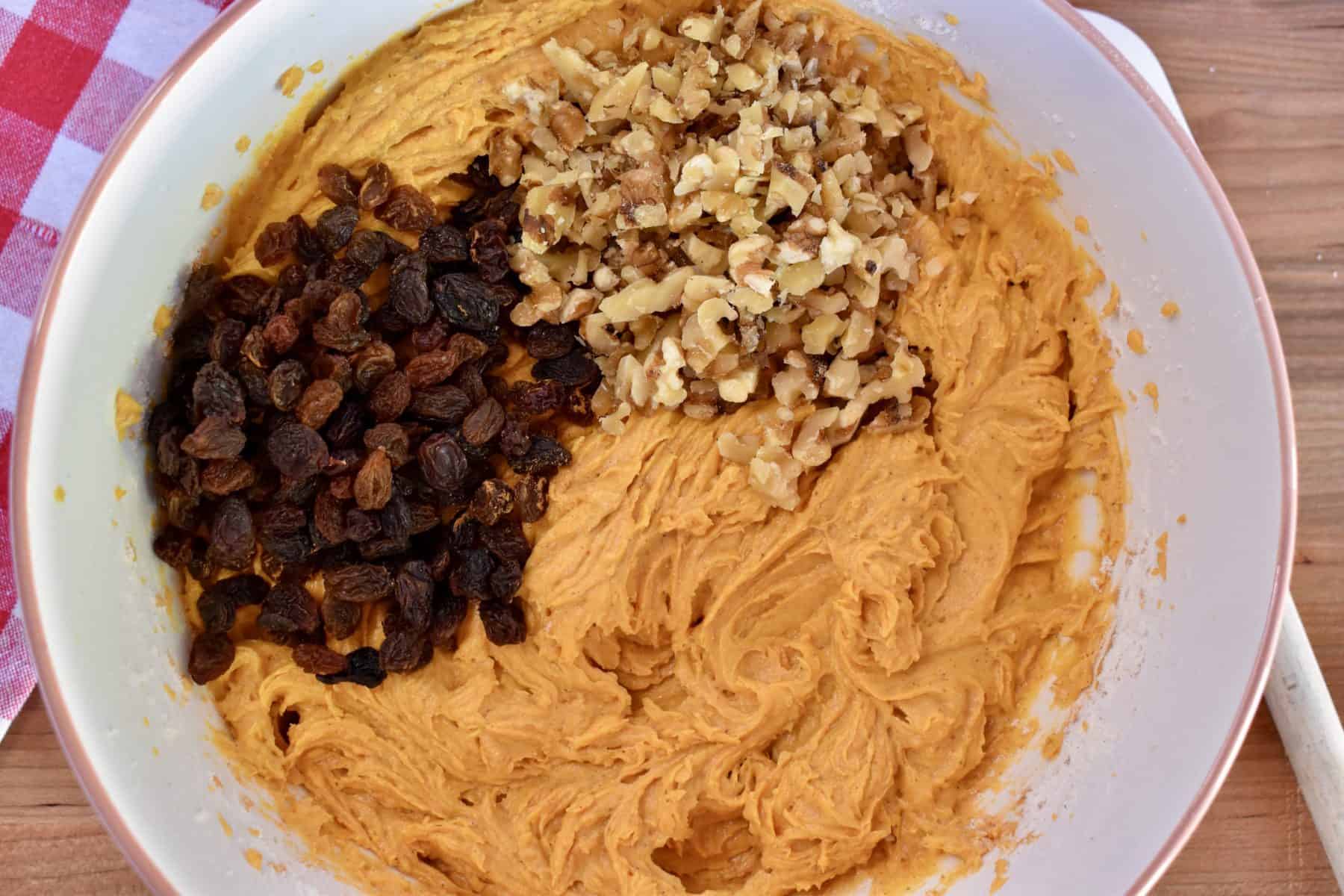 overhead photo of batter in the mixing bowl with raisins and walnuts on top. 