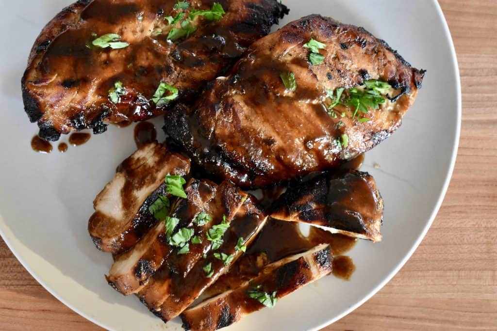 overhead photo of grilled marinated balsamic chicken with parsley on top.