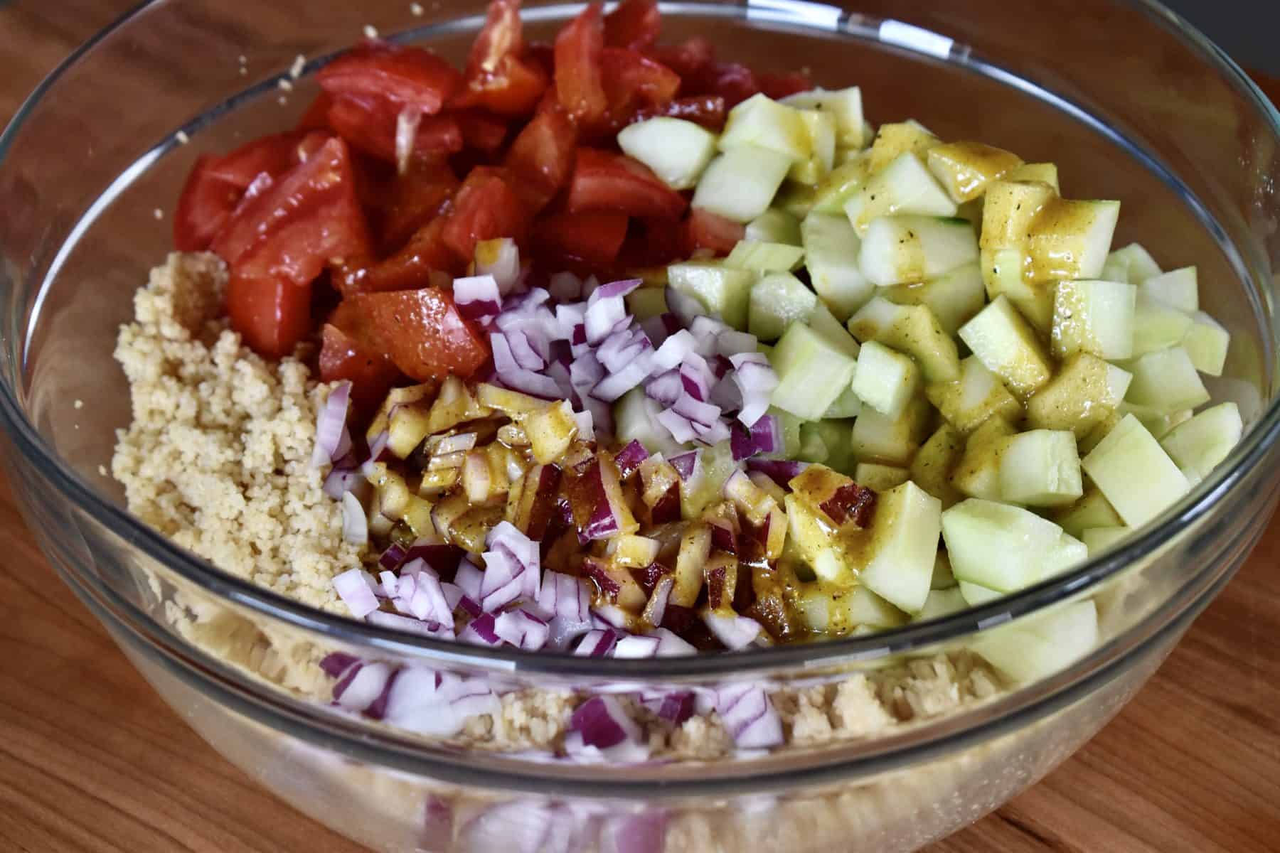 Dressing poured over the veggies in a glass bowl. 