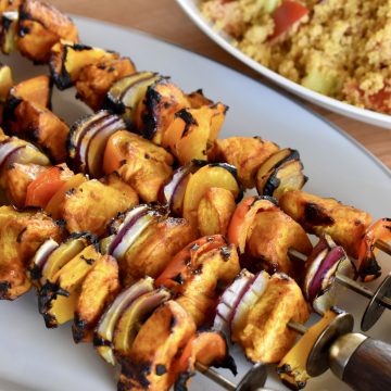 Grilled Chicken Kabob Skewers on a plate with couscous in the background.