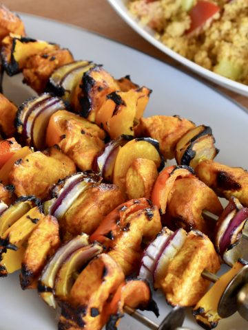 Grilled Chicken Kabob Skewers on a plate with couscous in the background.