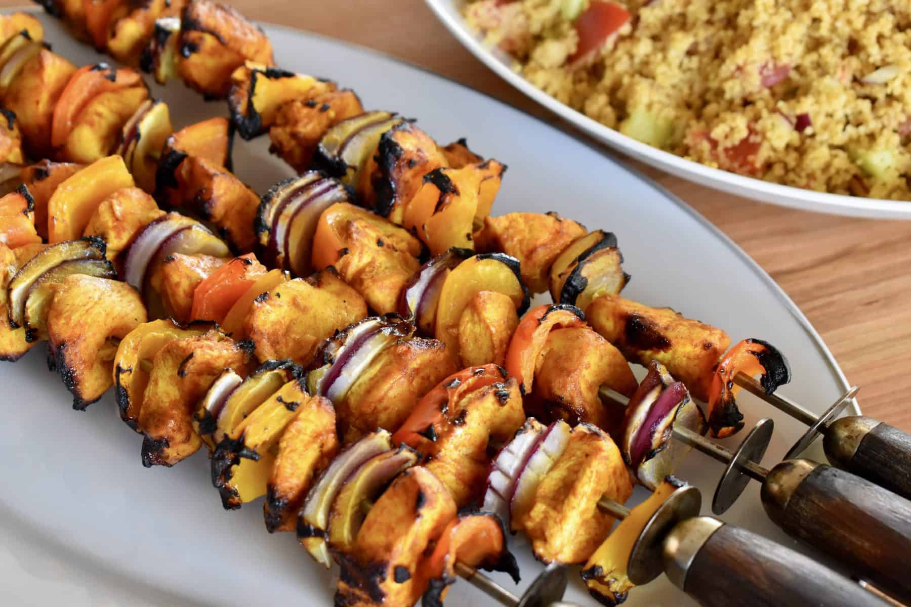 Grilled Chicken Kabob Skewers on a plate with couscous in the background. 