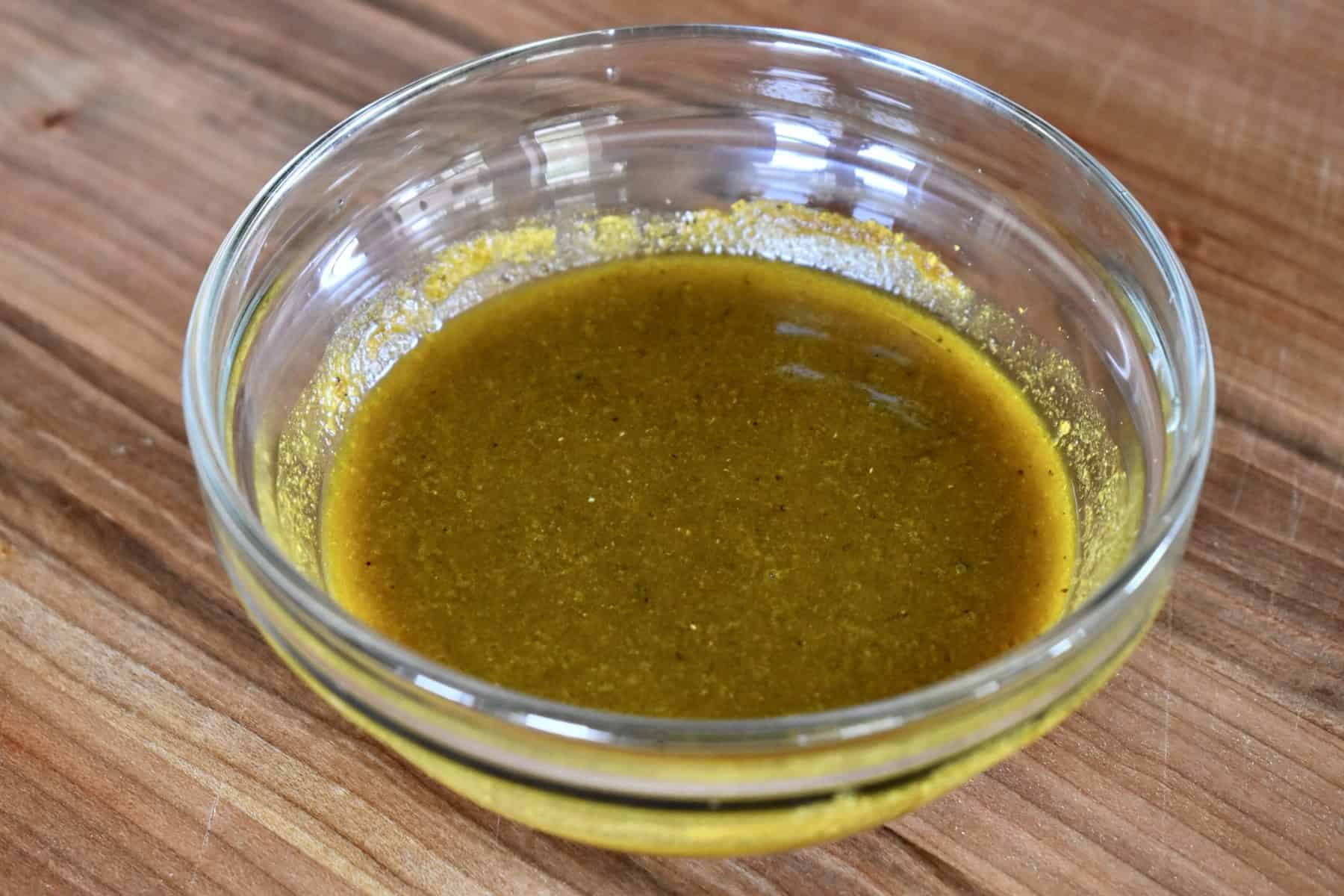 curry dressing in a small glass bowl on a wood cutting board. 