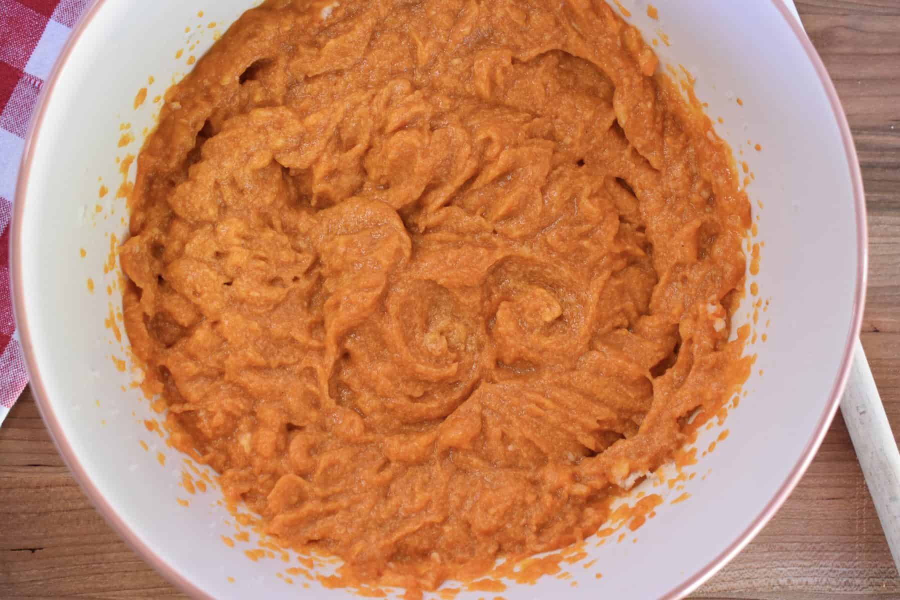 overhead photo of butter, sugar, pumpkin, and eggs all mixed together in a bowl. 