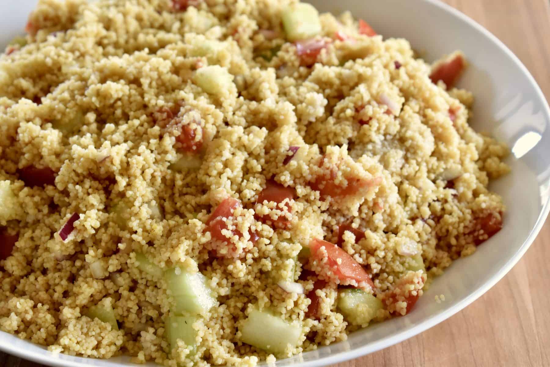 Curried Couscous with tomatoes, cucumbers, and onions in a white bowl. 