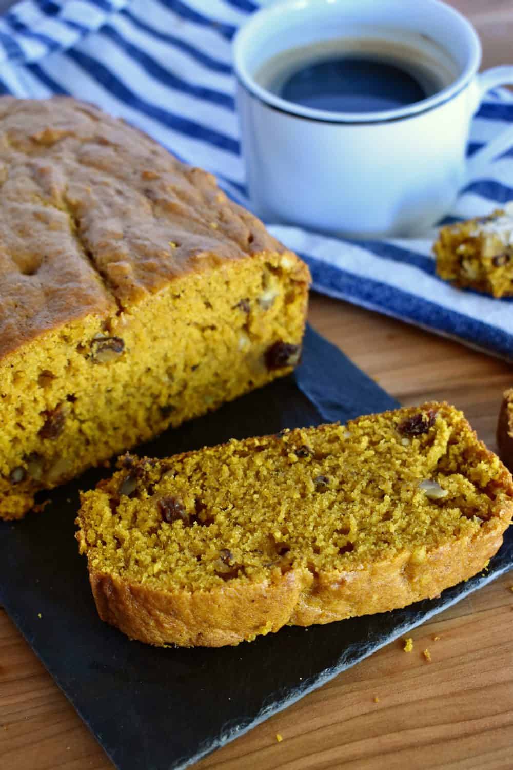 Pumpkin Walnut Raisin bread on the counter with a cup of coffee. 