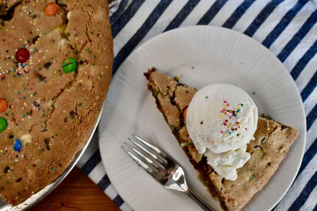 overhead photo of loaded cookie pie with a scoop of vanilla ice cream on top. 