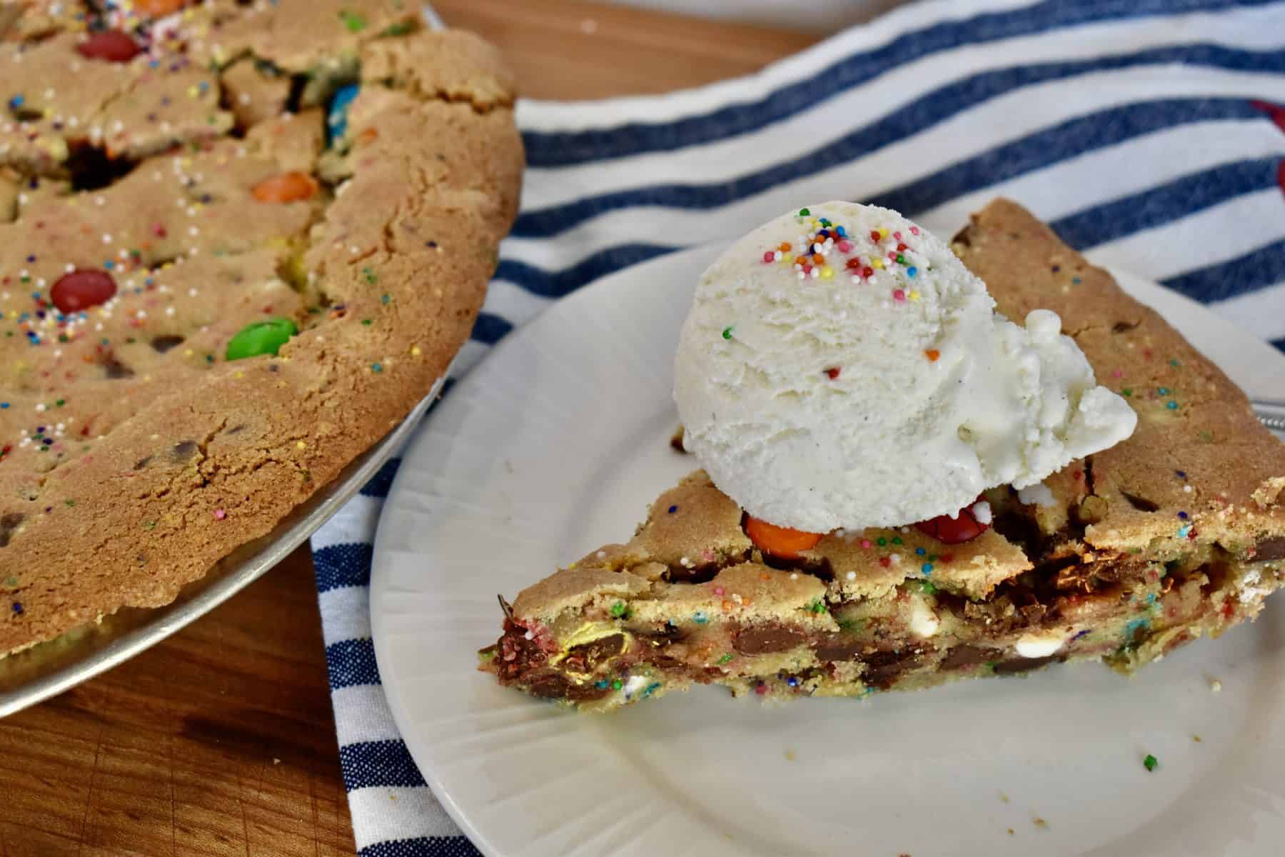 Loaded cookie pie on a plate with a scoop of vanilla ice cream. 
