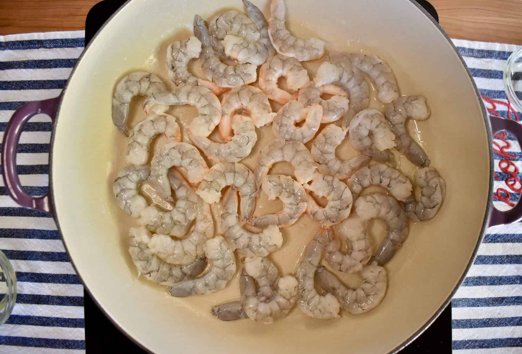 overhead photo of shrimp cooking in a large skillet. 