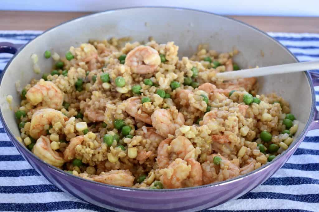 Shrimp fried brown rice in a pan with a spoon.