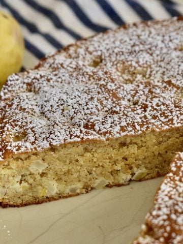 Almond Flour Pear Cake on a plate with pear in the background.
