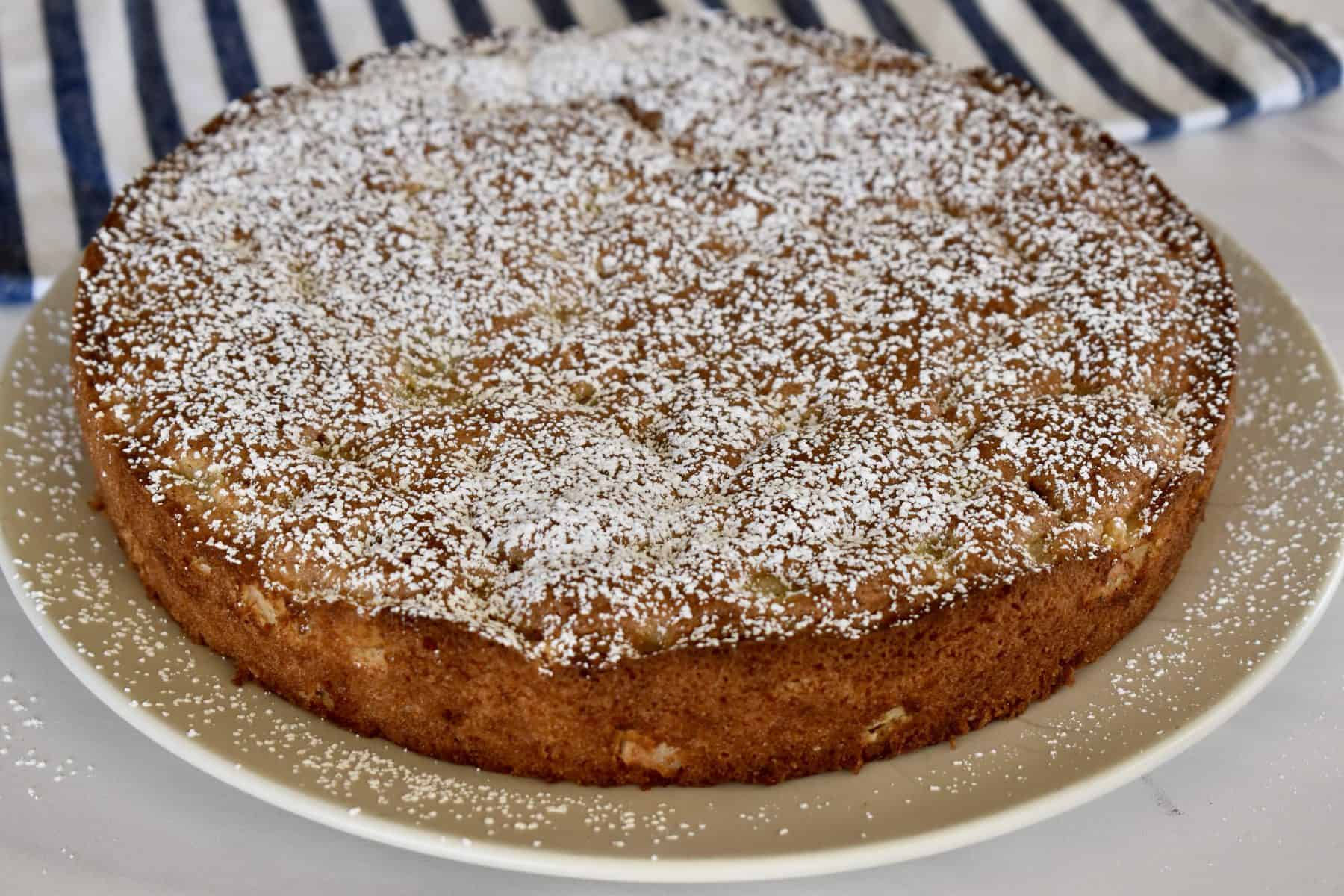 Almond Flour Pear cake dusted with powdered sugar on a round plate. 