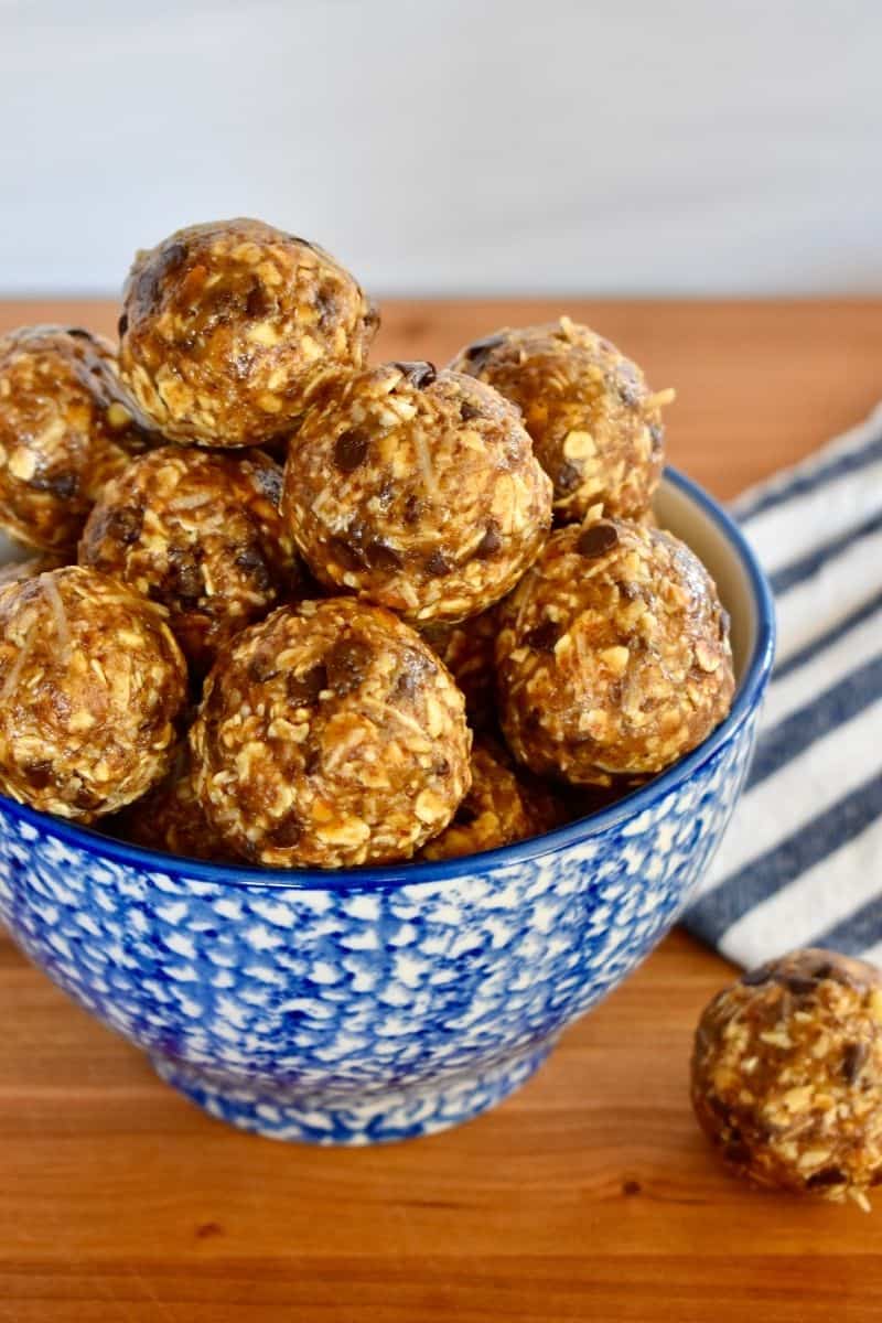 Chocolate Coconut Energy Balls in a blue bowl on a wooden countertop. 