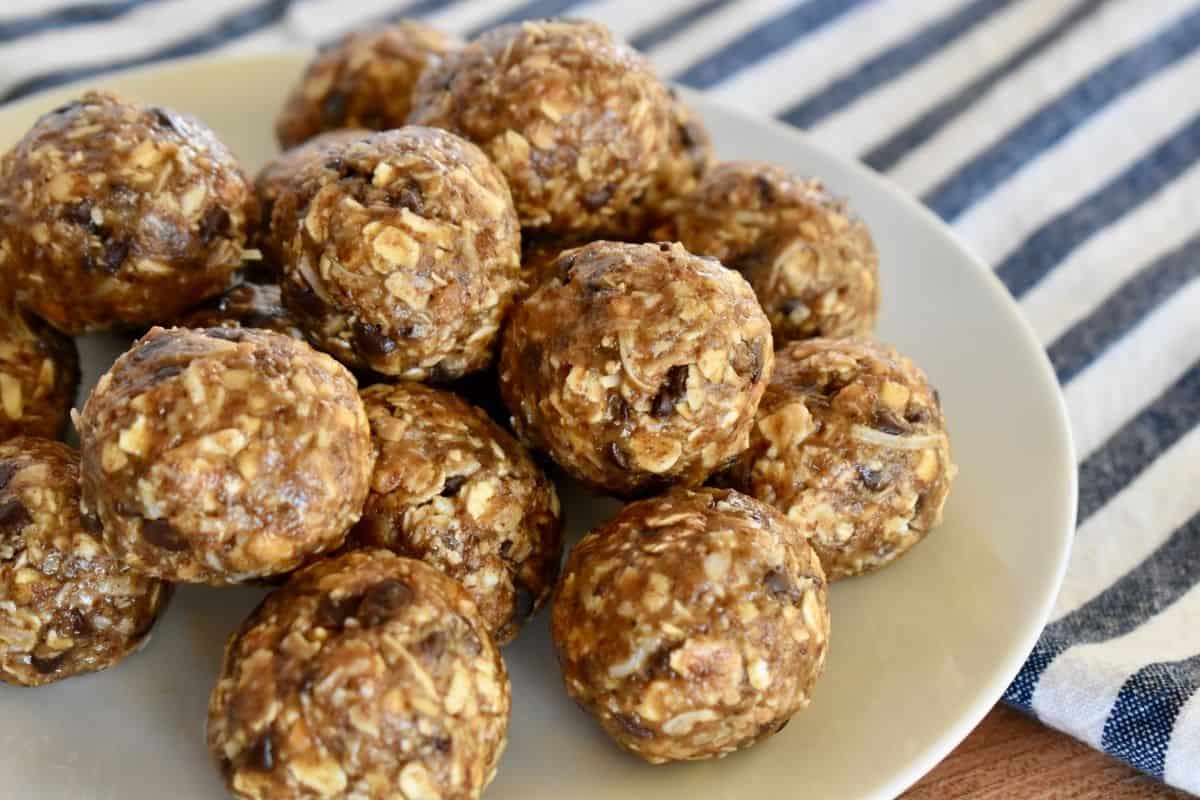 Chocolate coconut energy balls on a white plate with a striped napkin next to it. 