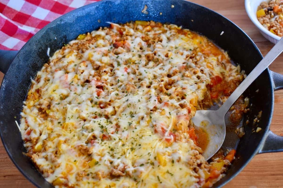 Stuffed Peppers Skillet recipe with melted cheese on top and a spoon in it. 