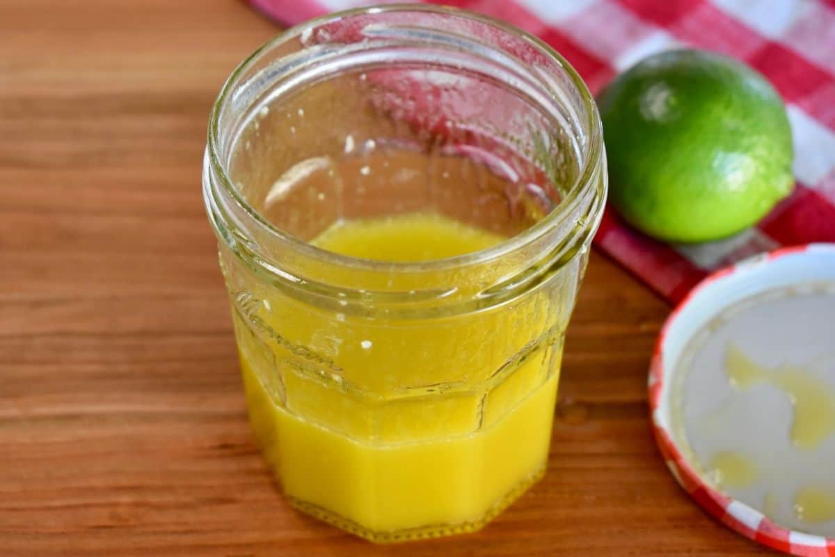 glass jar filled with dressing sitting on a wooden countertop. 