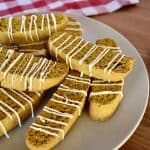 pumpkin biscotti with white chocolate drizzle on a white plate.