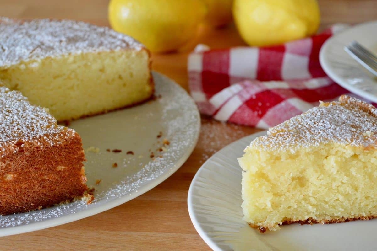 slice of italian lemon ricotta cake on a plate with a checkered napkin in the background. 