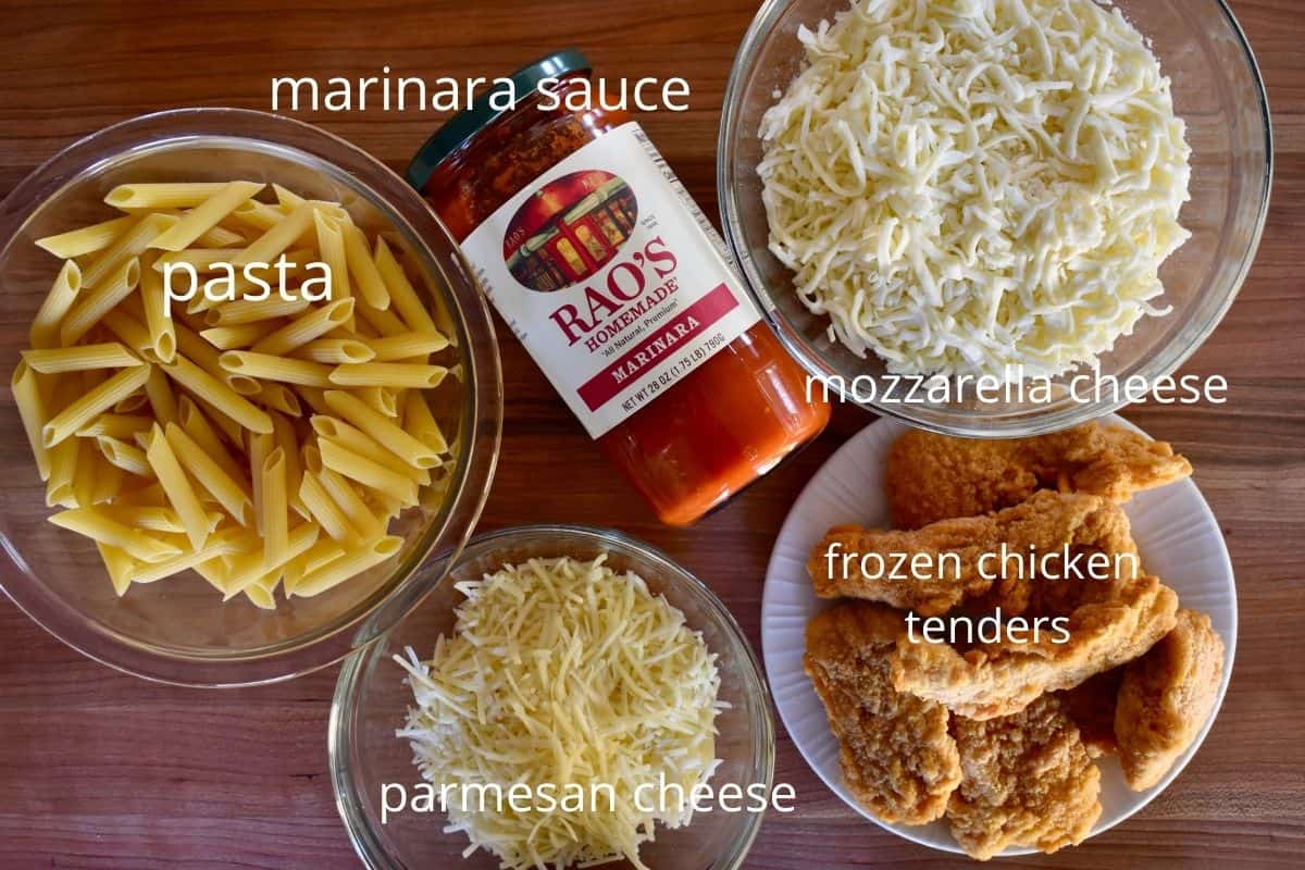 overhead photo of the ingredients required to make the recipe including marinara sauce, pasta, cheeses, and chicken tenders. 