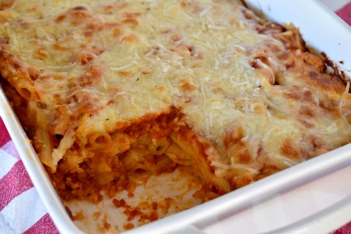 Chicken Parmesan Casserole in a white casserole dish with a piece cut out of it. 