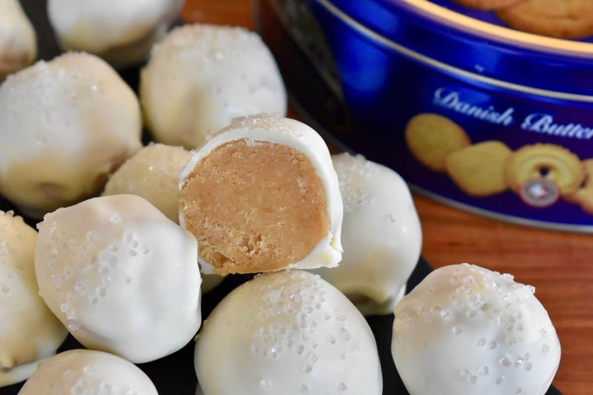 Butter cookie truffles piled on each other with a tin of Danish butter cookies in the background. 