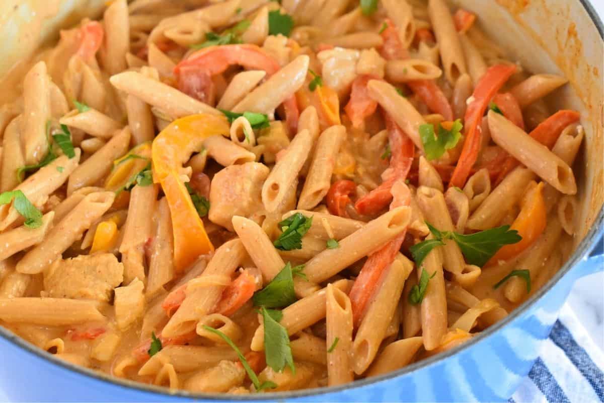 One pot chicken fajita pasta in a blue pot with parsley sprinkled overtop. 
