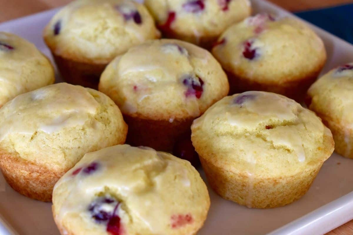 Nine cranberry orange muffins on a white serving plate. 