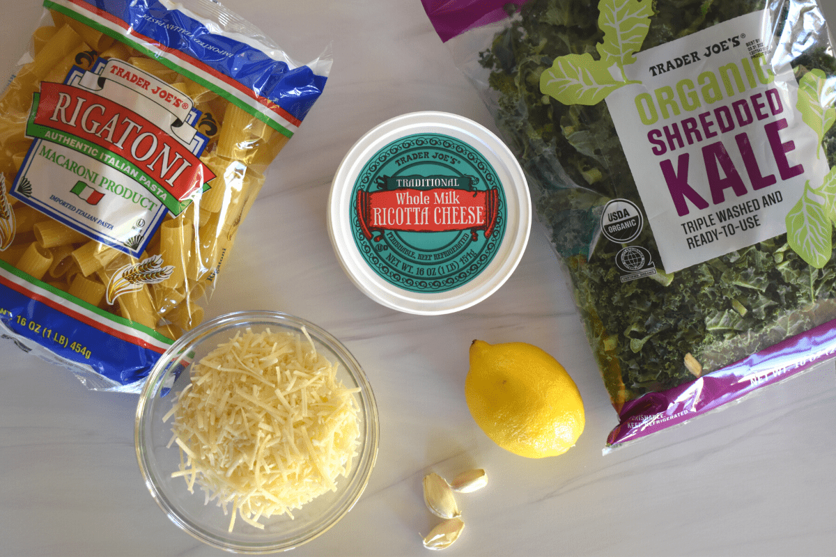 overhead photo of ingredients needed to make recipe including rigatoni, kale, and parmesan cheese. 