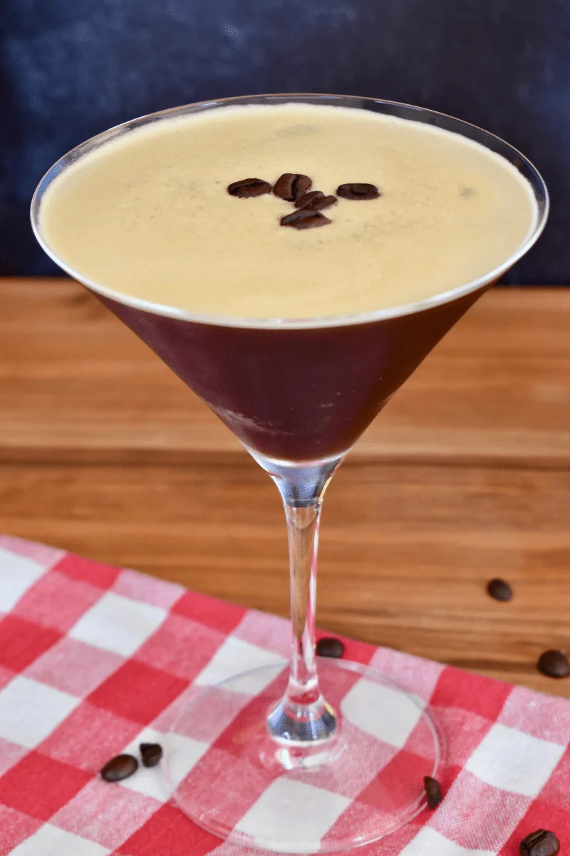 Espresso Martini with Kahlua in a martini glass on a wood surface with a checkered napkin. 